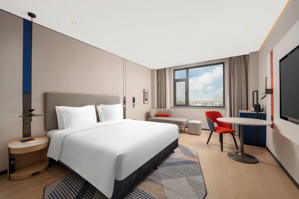 A modern hotel room with a large bed, a desk, a chair, and a view of the city through the window. - Holiday Inn Express Zhengzhou Nongye Road by IHG (Zhengzhou)