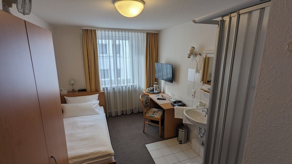 Una habitación de hotel con cama, escritorio, televisión y baño.