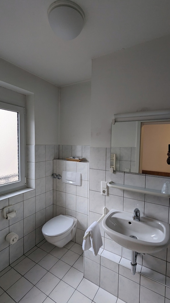 Un baño pequeño y limpio con inodoro, lavamanos y ventana.