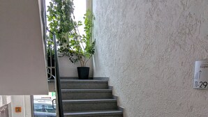 Una escalera con barandilla, una planta en maceta y un letrero con números colgado en la pared.