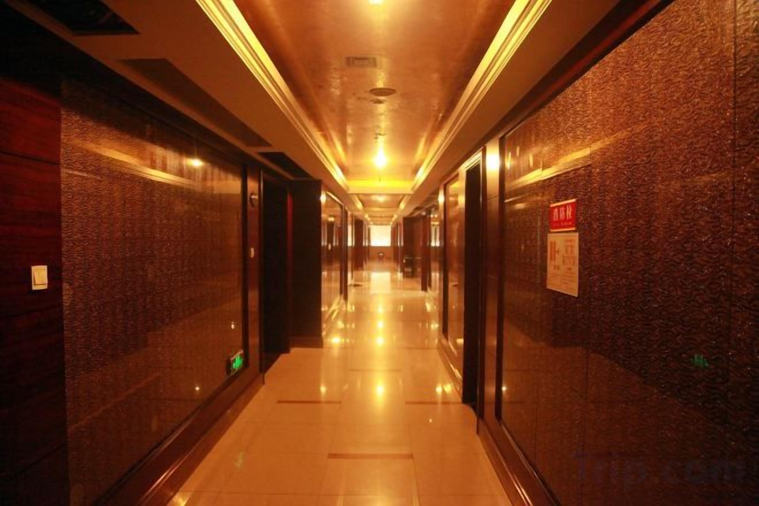 A corridor with a polished floor, mirrored walls, and a red sign on the right.