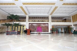 Un hall espacioso con un techo alto, un mural grande y una escalera que conduce a un nivel superior.