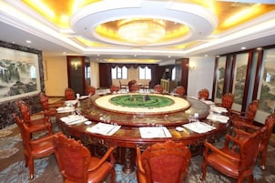 A conference room with a round table, chairs, and a chandelier.