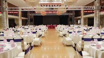 Ein Festsaal mit Reihen runder Tische, weißen Tischdecken und Stühlen mit blauen Bändern.