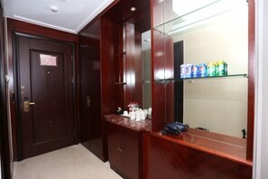 A wooden wardrobe with a mirror, a marble countertop, and a shelf with toiletries. - Guoyuan Hotel (Taizhou)