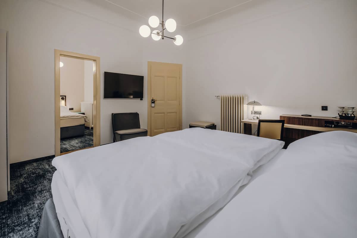 A hotel room with two beds, a TV, a desk, a chair, and a lamp.