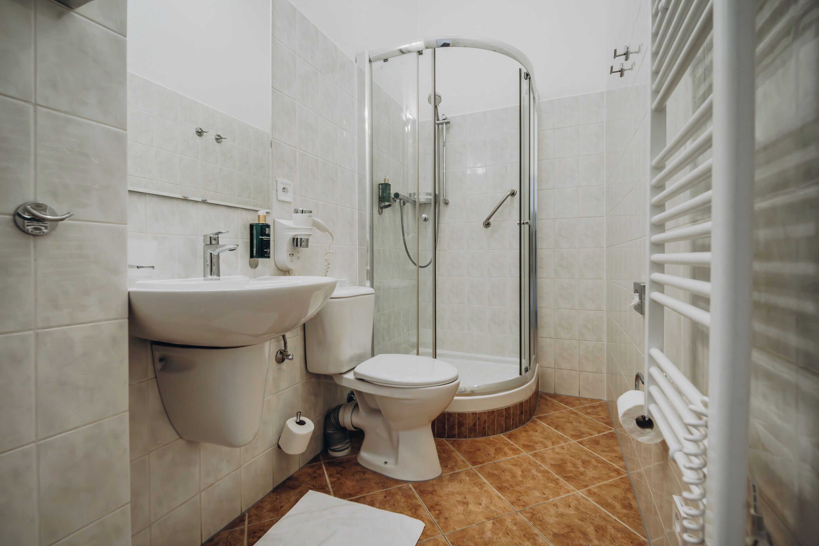 A modern bathroom with a glass-enclosed shower, a sink, and a toilet.