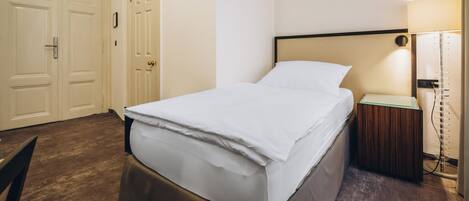A hotel room with a bed, a nightstand, a lamp, and a wardrobe.