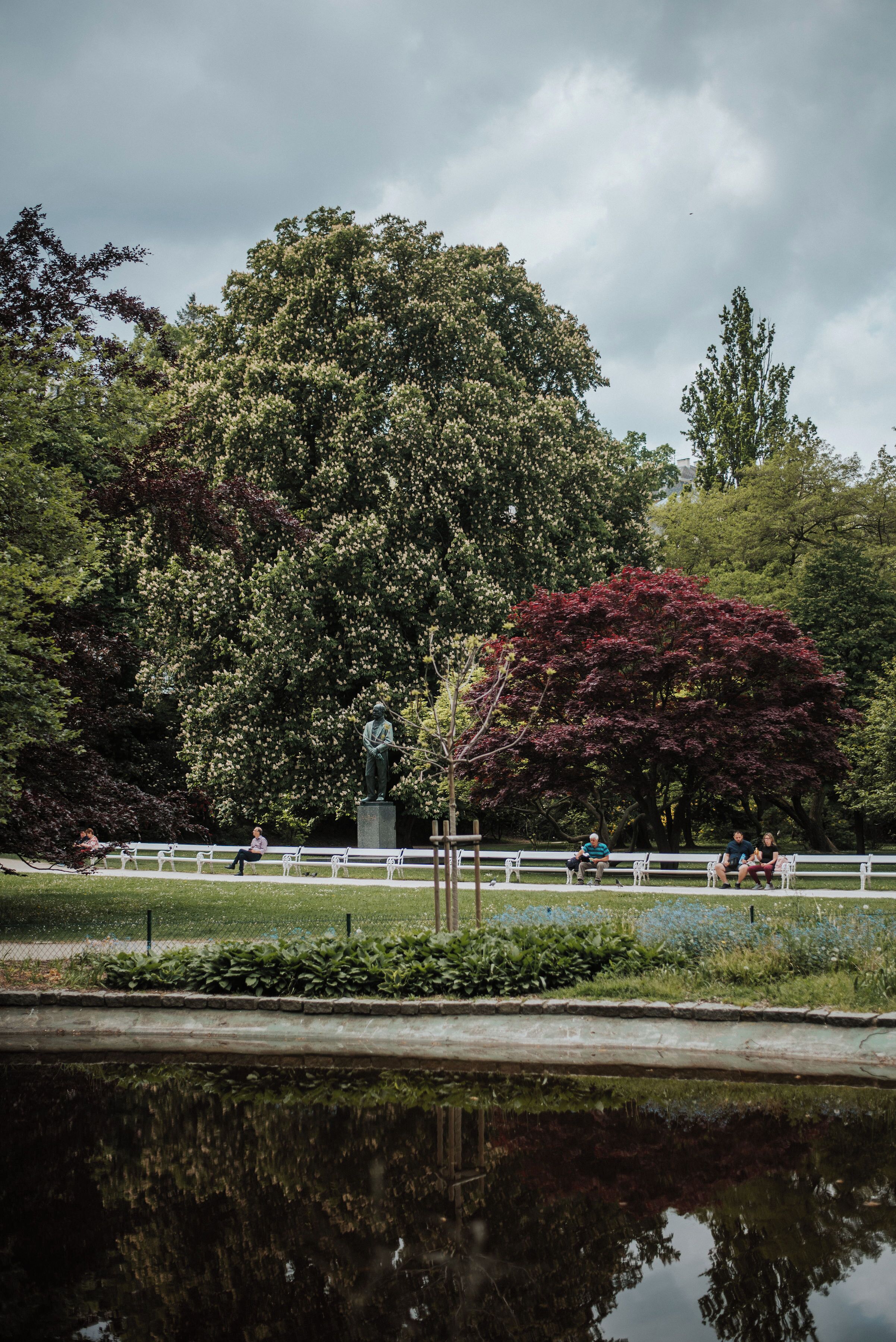 Ein Park mit einer Statue, Bänken und einem Teich.
