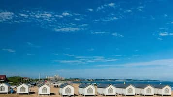Una hilera de cabañas de playa con vista despejada al mar y un edificio distante.