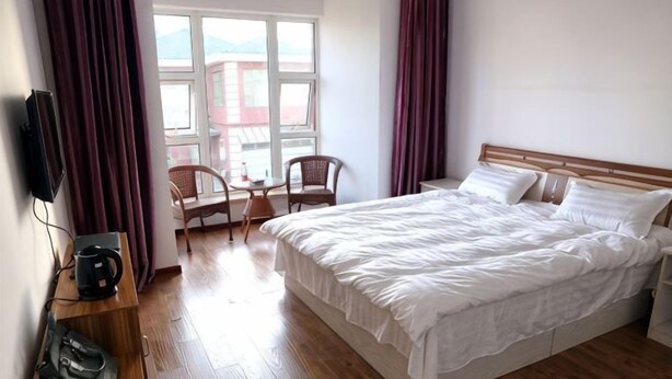 A hotel room with a large bed, a desk with a chair, a TV, and a window with curtains. - Dalian Mong Kok Express Hotel (Dalian)