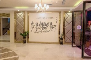 A lobby with a large wall-mounted artwork of horses, a chandelier, and a reception desk. - Baise Little Orange Hotel (Baise)