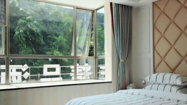 A bedroom with a large window, a bed with striped bedding, and a headboard with a diamond pattern. - Yan Nian Hotel (Baise)