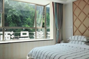 A bedroom with a large window, a bed with striped bedding, and a headboard with a diamond pattern. - Yan Nian Hotel (Baise)