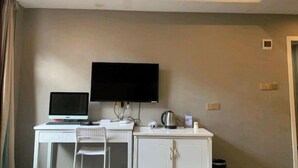 A hotel room with a desk, a computer, a television, a chair, and a cabinet. - Yan Nian Hotel (Baise)