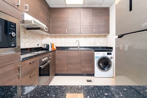 A modern kitchen with wooden cabinets, a built-in oven, a washing machine, and a stainless steel refrigerator.