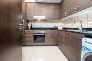 Een moderne keuken met houten kastjes, een inbouwoven, een wasmachine en een betegelde spatwand.
