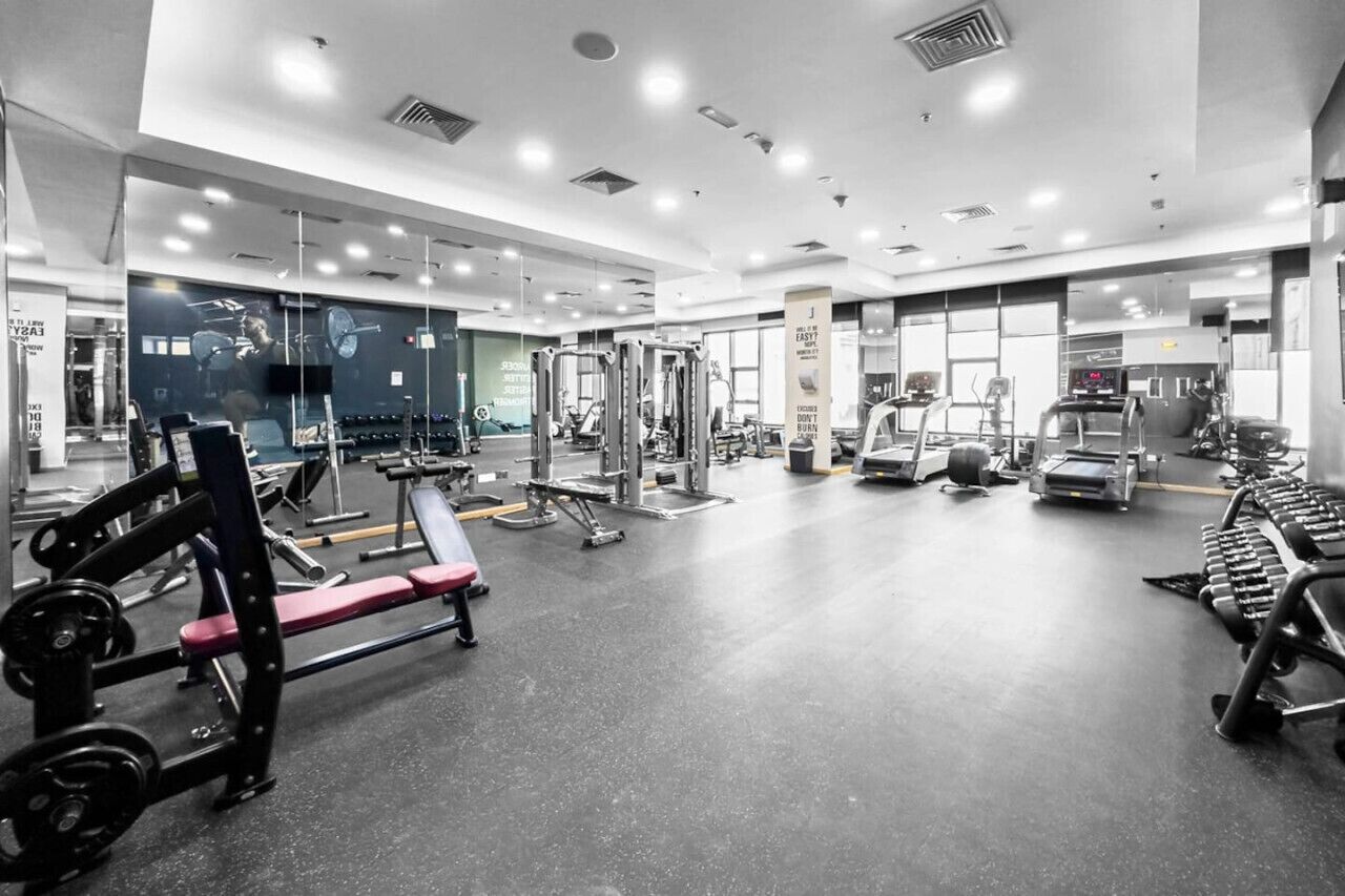 Een moderne sportschool met diverse fitnessapparaten, spiegels en een schoon, goed verlicht interieur.