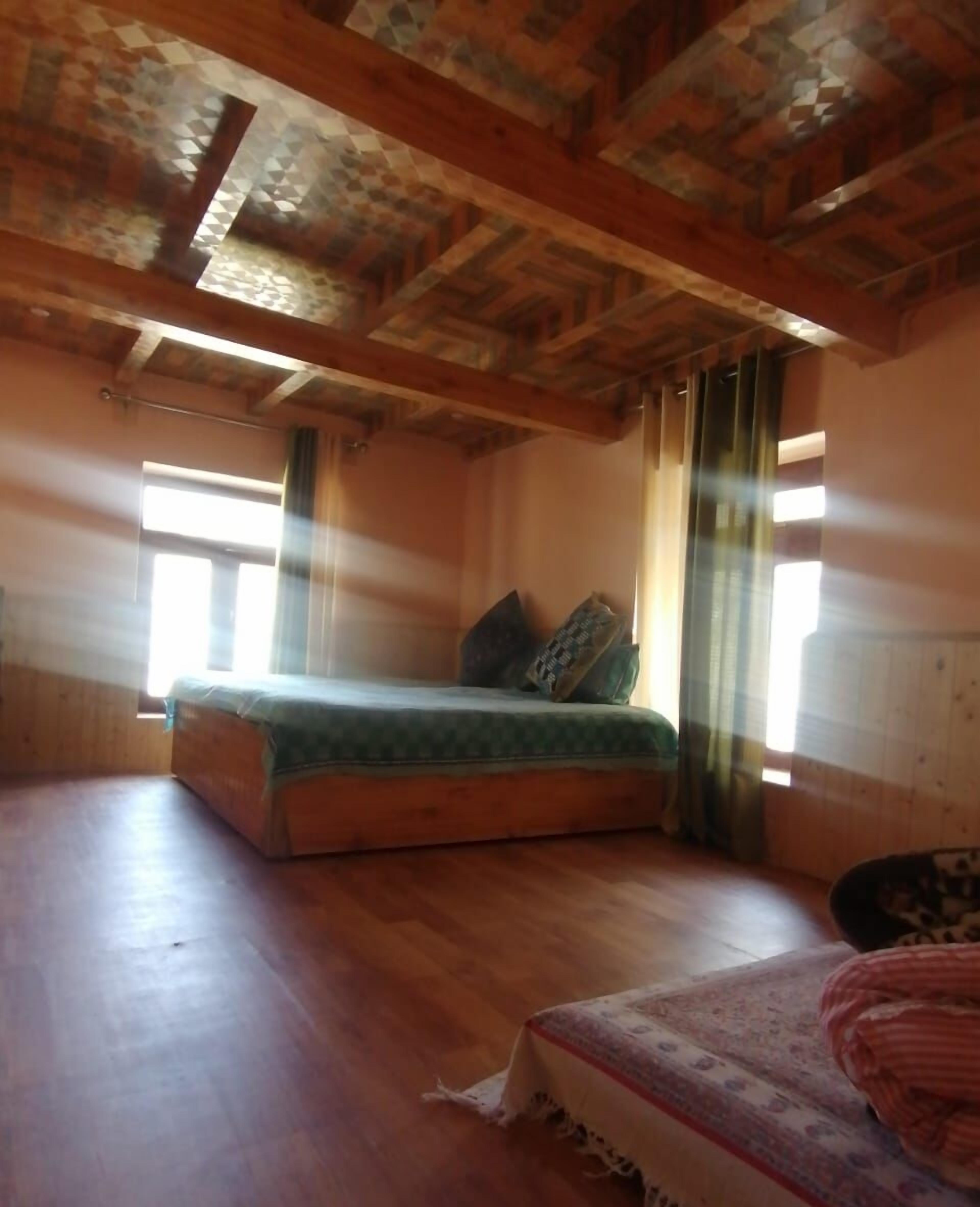A room with a bed, a window, and a wooden ceiling.