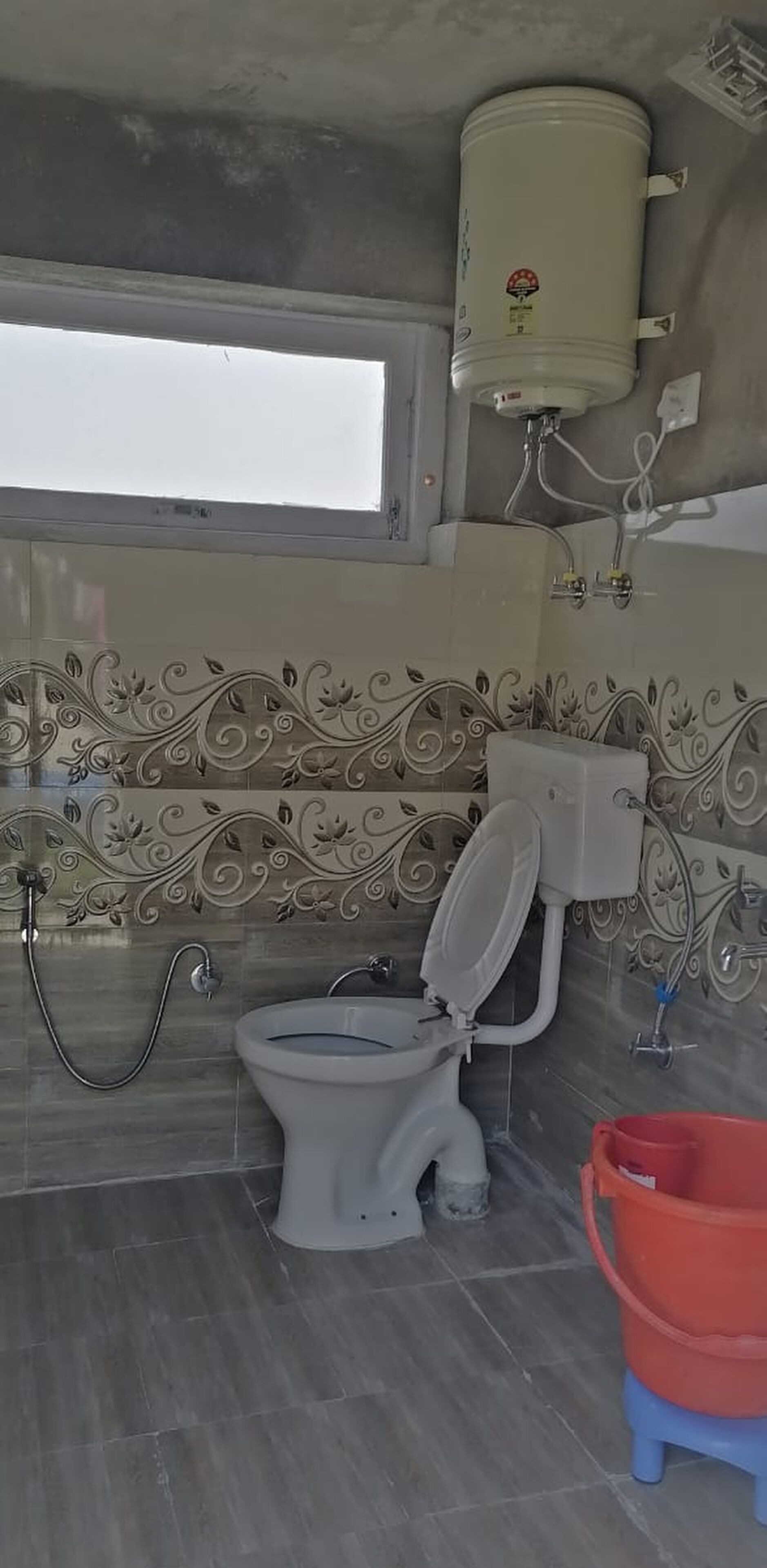 Une salle de bain équipée de toilettes, d’un bidet et d’un chauffe-eau.