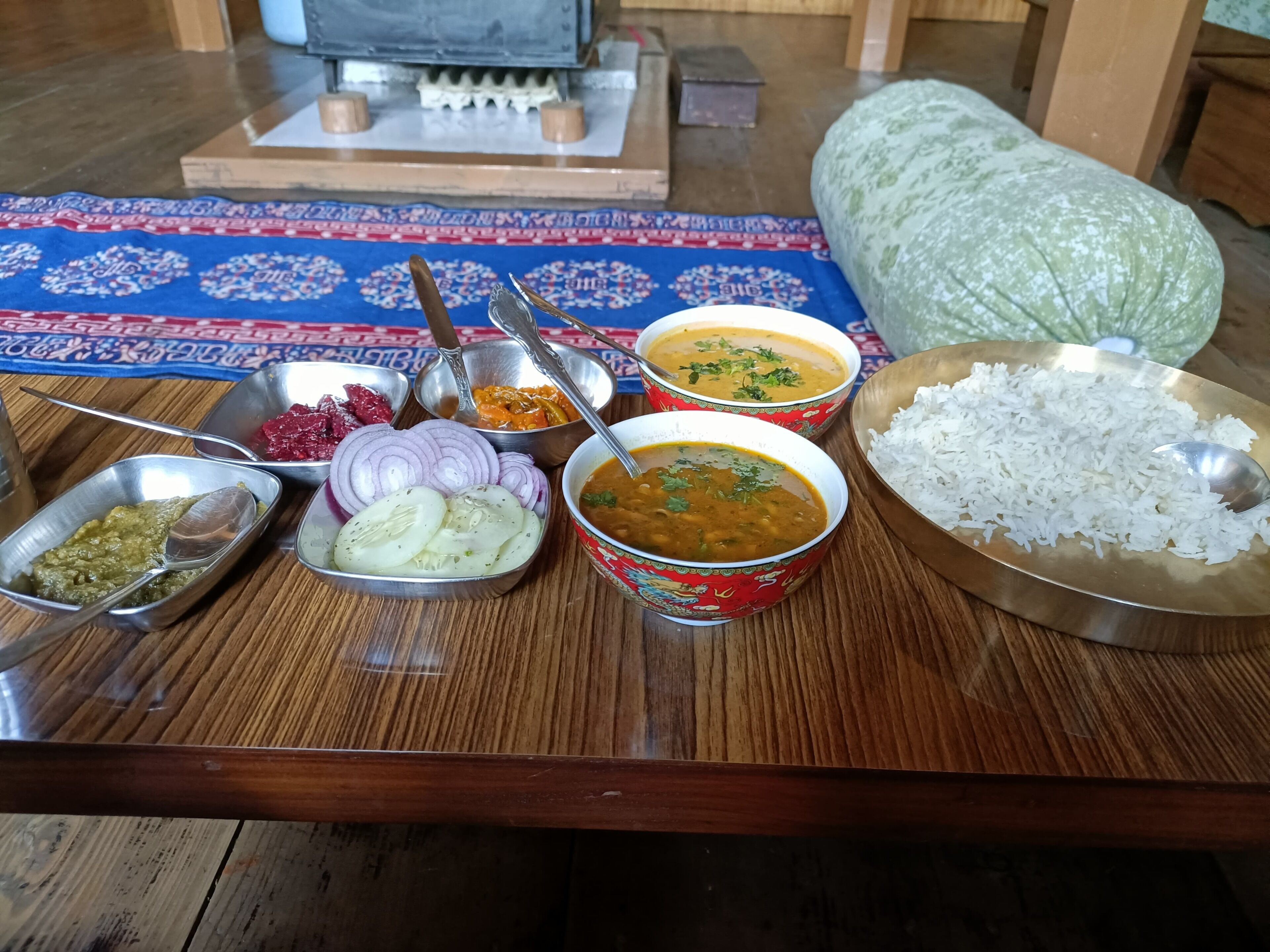 A wooden table with various dishes including rice, curry, and vegetables.