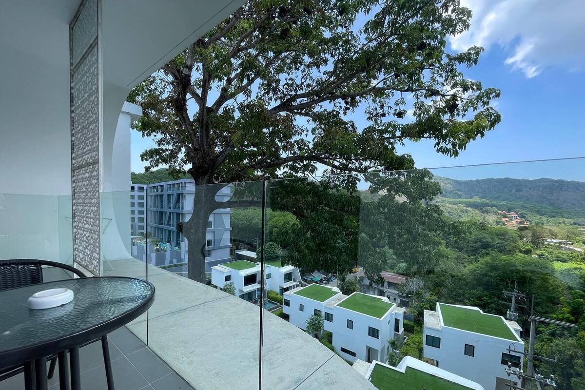 A balcony with a glass partition, a dining table, and chairs.