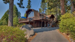 A cabin with a wooden exterior, a balcony, and a staircase leading to an upper level.
