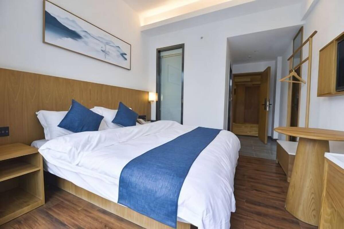 Een hotelkamer met een bed, nachtkastjes, een spiegel en een schilderij aan de muur.