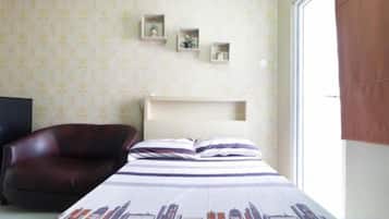 A bedroom with a bed, a chair, a bedside table, and a window.