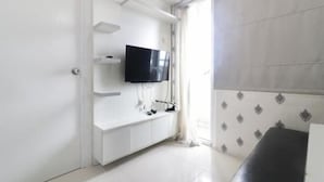 Een moderne woonkamer met een flatscreen televisie aan een witte tv-kast, een zwarte bank en een behang met patroon.