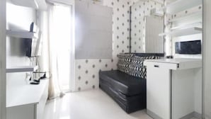 Een moderne, minimalistische kamer met een bank, een klein tafeltje en een grote spiegel.
