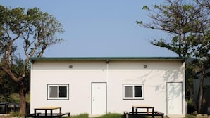 Un bâtiment à deux étages, doté d’un toit végétalisé, de deux fenêtres au rez-de-chaussée et d’une porte. On y trouve deux tables à l’extérieur, devant l’entrée.