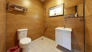 Une salle de bain avec des murs en bois, des toilettes, un lavabo et une douche.