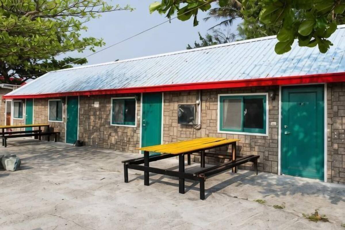 A building with a red roof, green doors, and a concrete floor with benches.