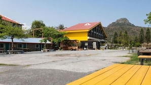 Un bâtiment avec un toit rouge, un bâtiment jaune en arrière-plan et une montagne au loin.
