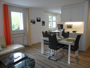 Una cocina moderna con armarios blancos, una mesa de comedor con cuatro sillas y una mesa de centro de mármol.