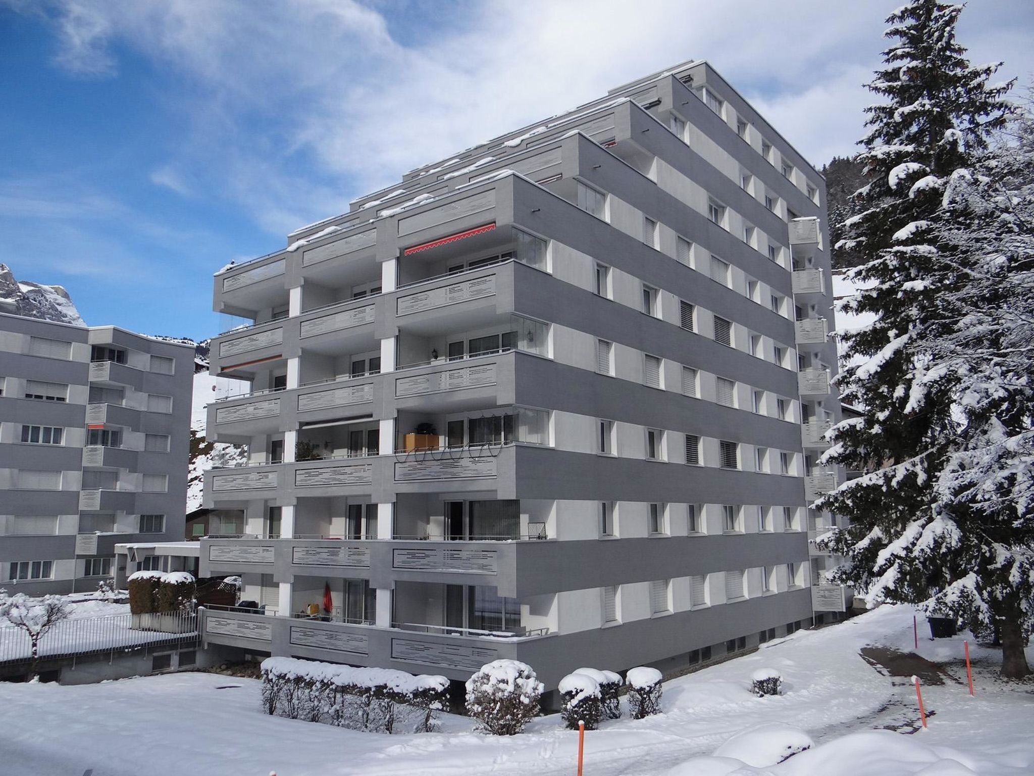 Ein mehrstöckiges Hotel mit Balkonen, verschneiter Umgebung und blauem Himmel.