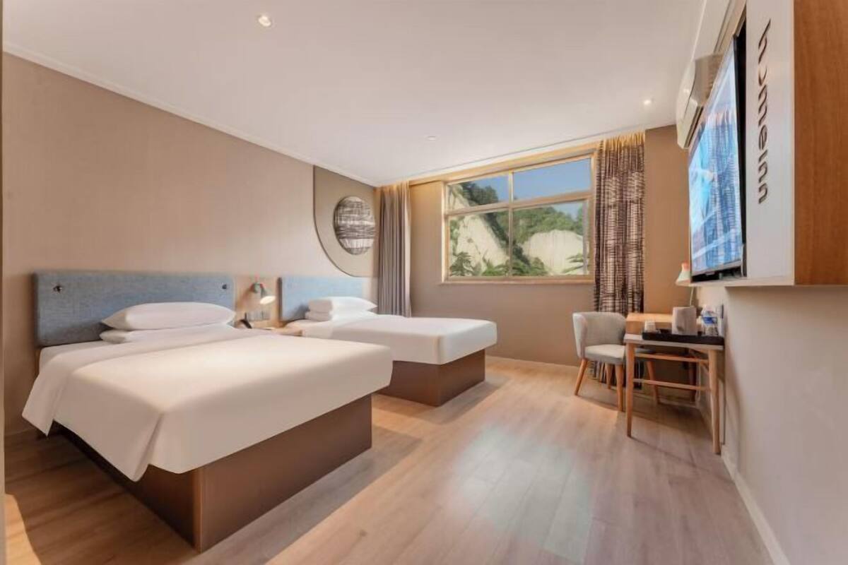 Une chambre d’hôtel moderne équipée de deux lits, d’un bureau et d’une chaise.