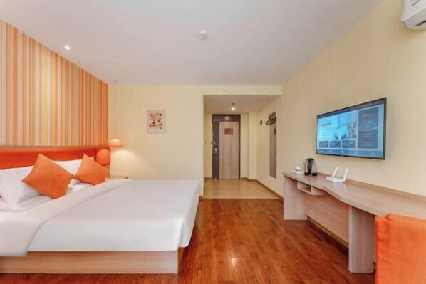Une chambre d’hôtel comprenant un lit, un bureau, une télévision et une porte donnant sur une autre pièce.
