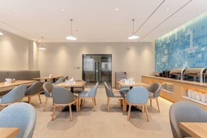 Un comedor moderno con mesas y sillas, un mostrador para buffet y un amplio ventanal.