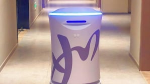 A modern, cylindrical trash bin with a purple abstract design, located in a hallway with a light-colored floor and beige walls. - Home Inn (Huayin Huashan Scenic Area Branch) (Huayin)