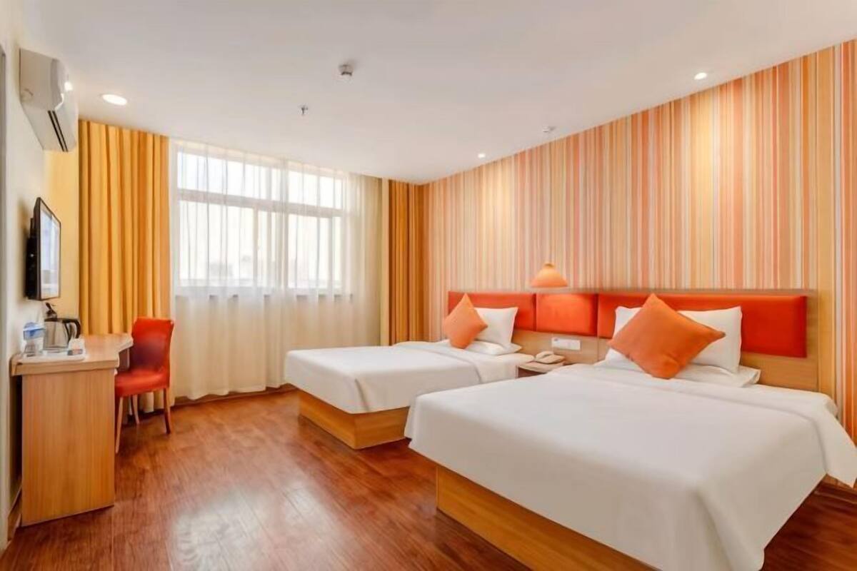 Une chambre d’hôtel avec deux lits, un bureau, une chaise et un téléviseur.