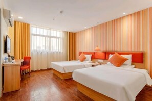 A hotel room with two beds, a desk, a chair, and a TV.