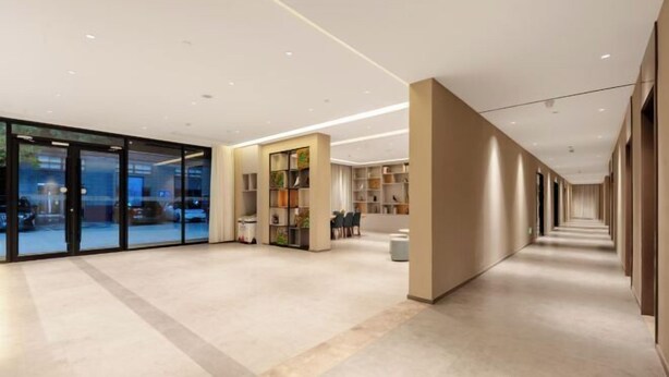 A modern hotel lobby with a glass entrance, a seating area with tables and chairs, and a long corridor with doors. - Home Inn (Huayin Huashan Scenic Area Branch) (Huayin)