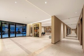 A modern hotel lobby with a glass entrance, a seating area with tables and chairs, and a long corridor with doors. - Home Inn (Huayin Huashan Scenic Area Branch) (Huayin)