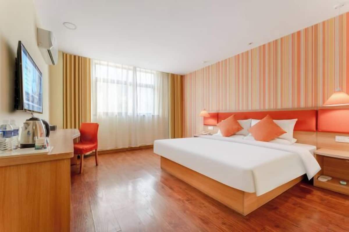 Une chambre d’hôtel équipée d’un lit, d’un bureau avec une bouilloire, d’une chaise et d’un téléviseur.