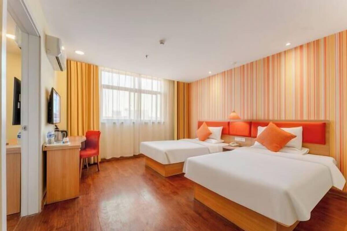 Une chambre d’hôtel avec deux lits, un bureau, une chaise et un téléviseur.