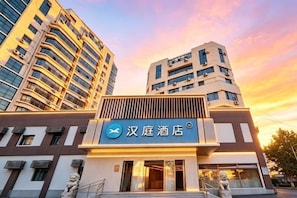 A hotel with a prominent sign, modern architecture, and a staircase leading to the entrance. - HanTing Hotel (Qingdao Zhanqiao Railway Station East Square) (Qingdao)