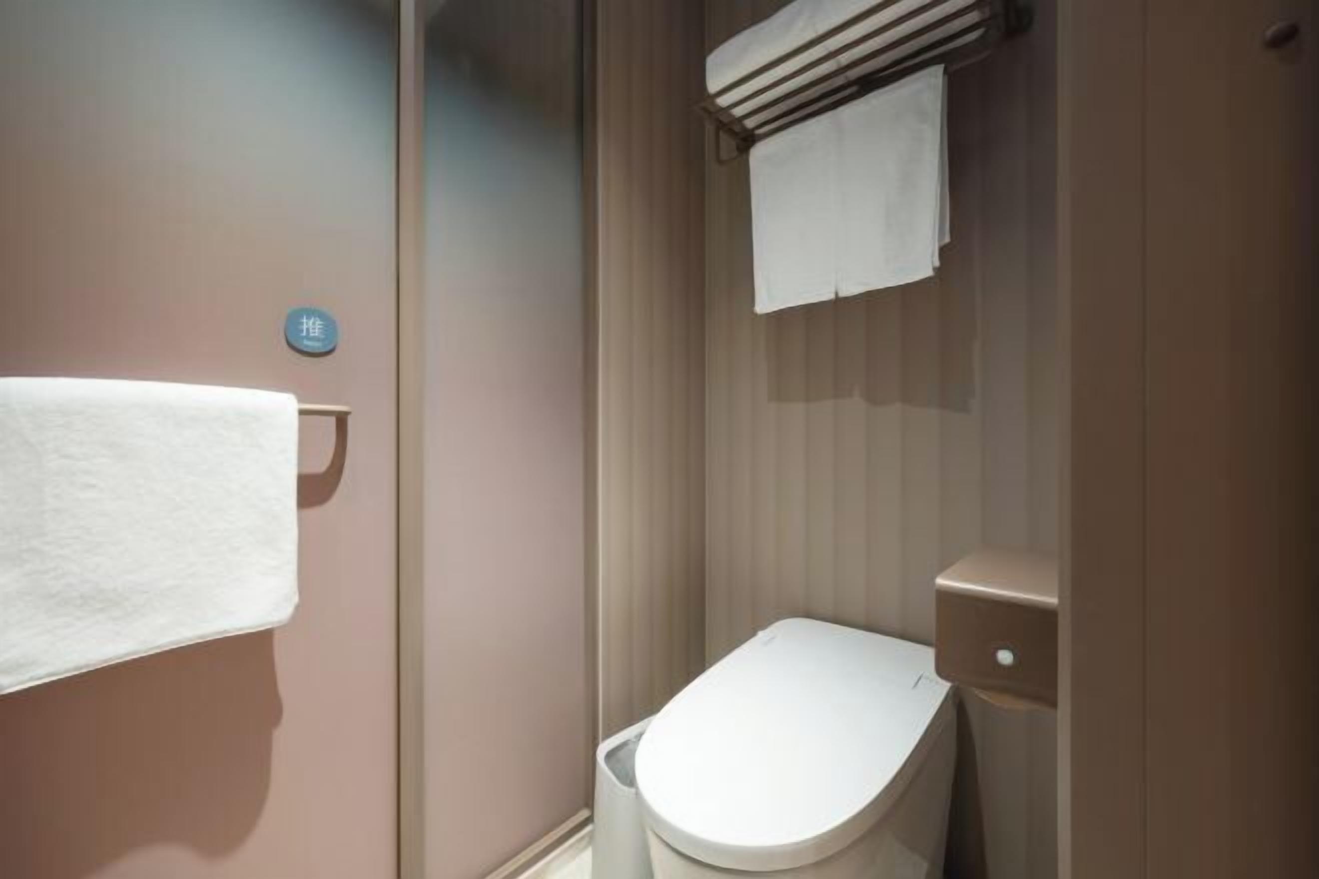 A bathroom with a toilet, a towel rack, and a wall-mounted towel.