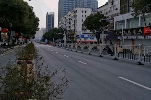 A city street with buildings, a fence, and a clear sky.